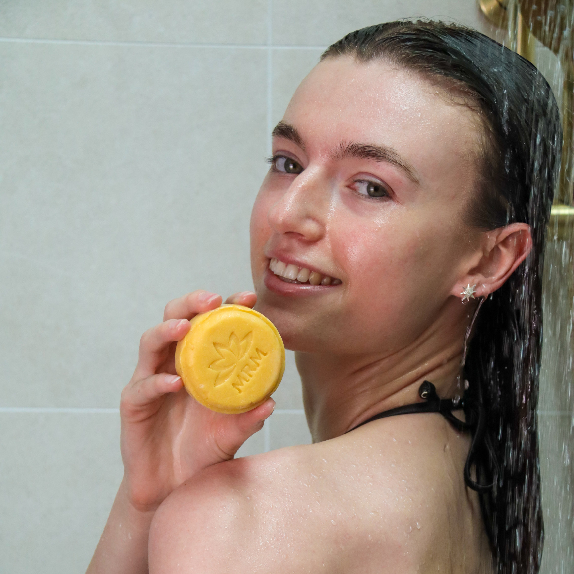 lady holding a shampoo bar in the shower
