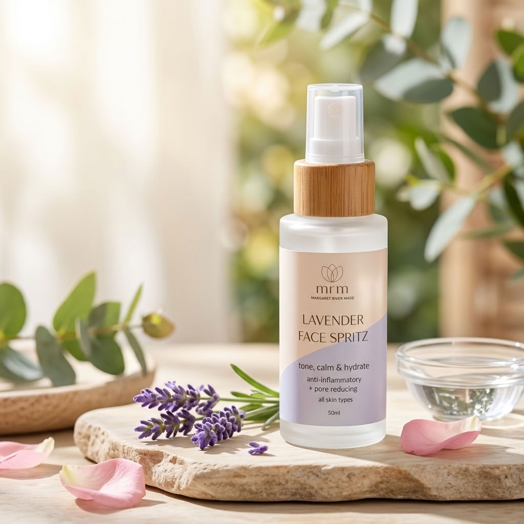 A bottle of mfm Lavender Face Spritz set on a stone tray with lavender sprigs, pink rose petals, and a small glass bowl, against a soft-focus background of green leaves and warm light.