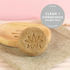An Anti-Dandruff Shampoo Bar with an engraved logo, placed on a wooden comb with a beige background. There is a badge indicating &
