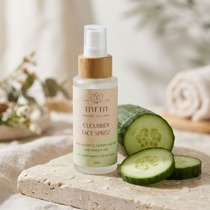 MRM Cucumber Face Spritz bottle with a bamboo cap, set on a stone slab next to fresh cucumber slices, with a soft spa-like background.