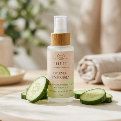 MRM Cucumber Face Spritz in a frosted glass bottle with a bamboo cap, styled on a marble tray with fresh cucumber slices in a warm, softly blurred spa-like setting.