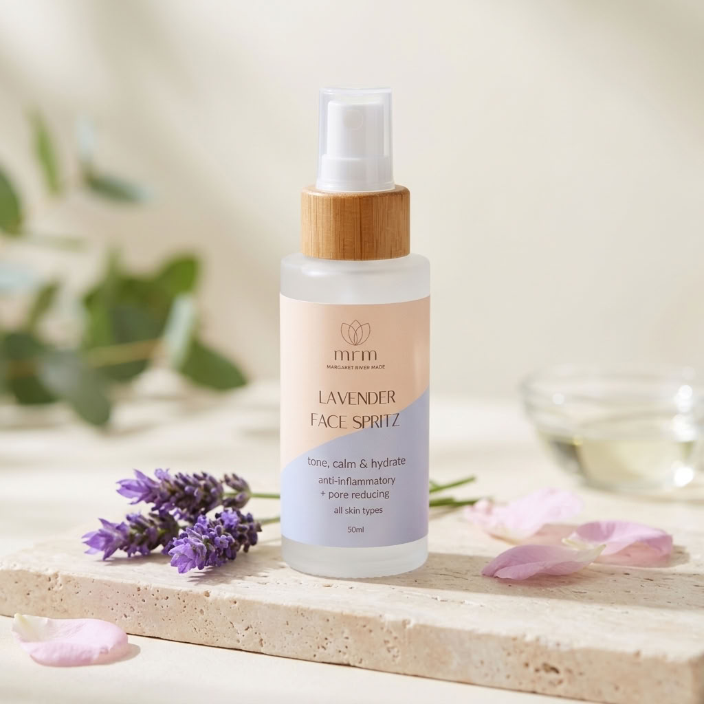 A 50ml bottle of MIMI Lavender Face Spray with a bamboo cap, styled on a stone slab with lavender sprigs and pink petals.
